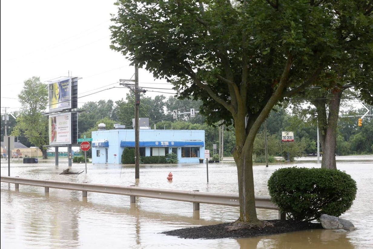A flooded street scene with businesses partly submerged in floodwater