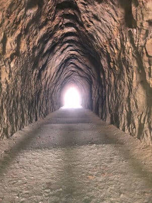 Looking down the length of the rough-cut rock tunnel at Blackhand Gorge to the bright exit