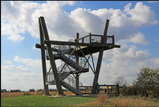 Tall wooden observation tower with spiral stairs against a blue sky
