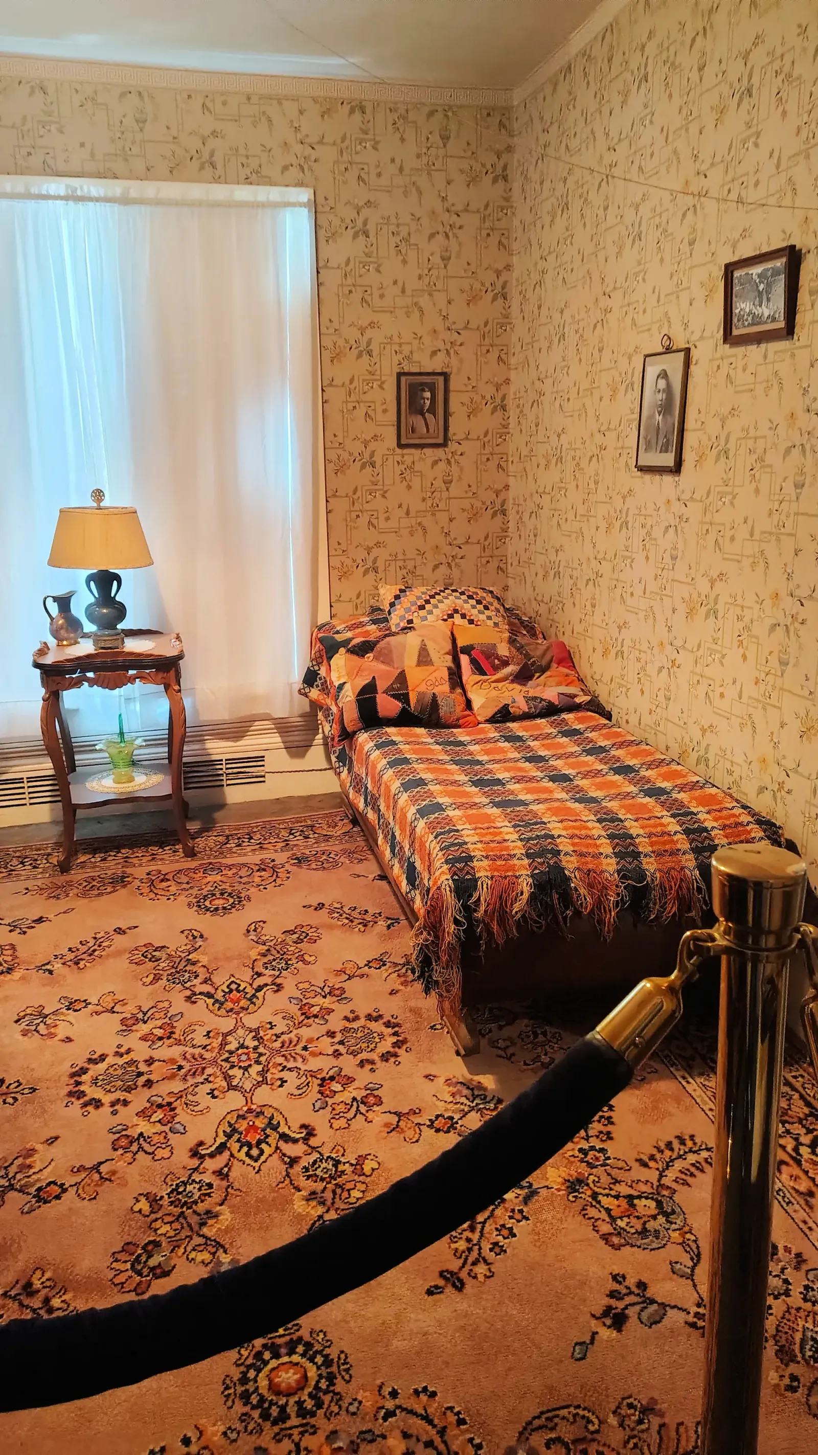 Single iron bed with a striped quilt in a small historic bedroom