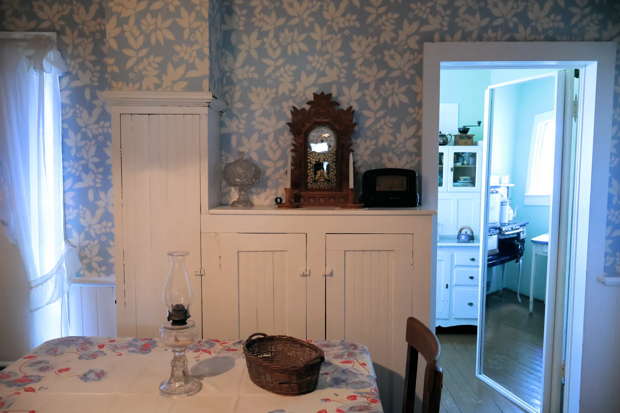Kitchen interior with blue wallpaper, white cabinets, and a small table
