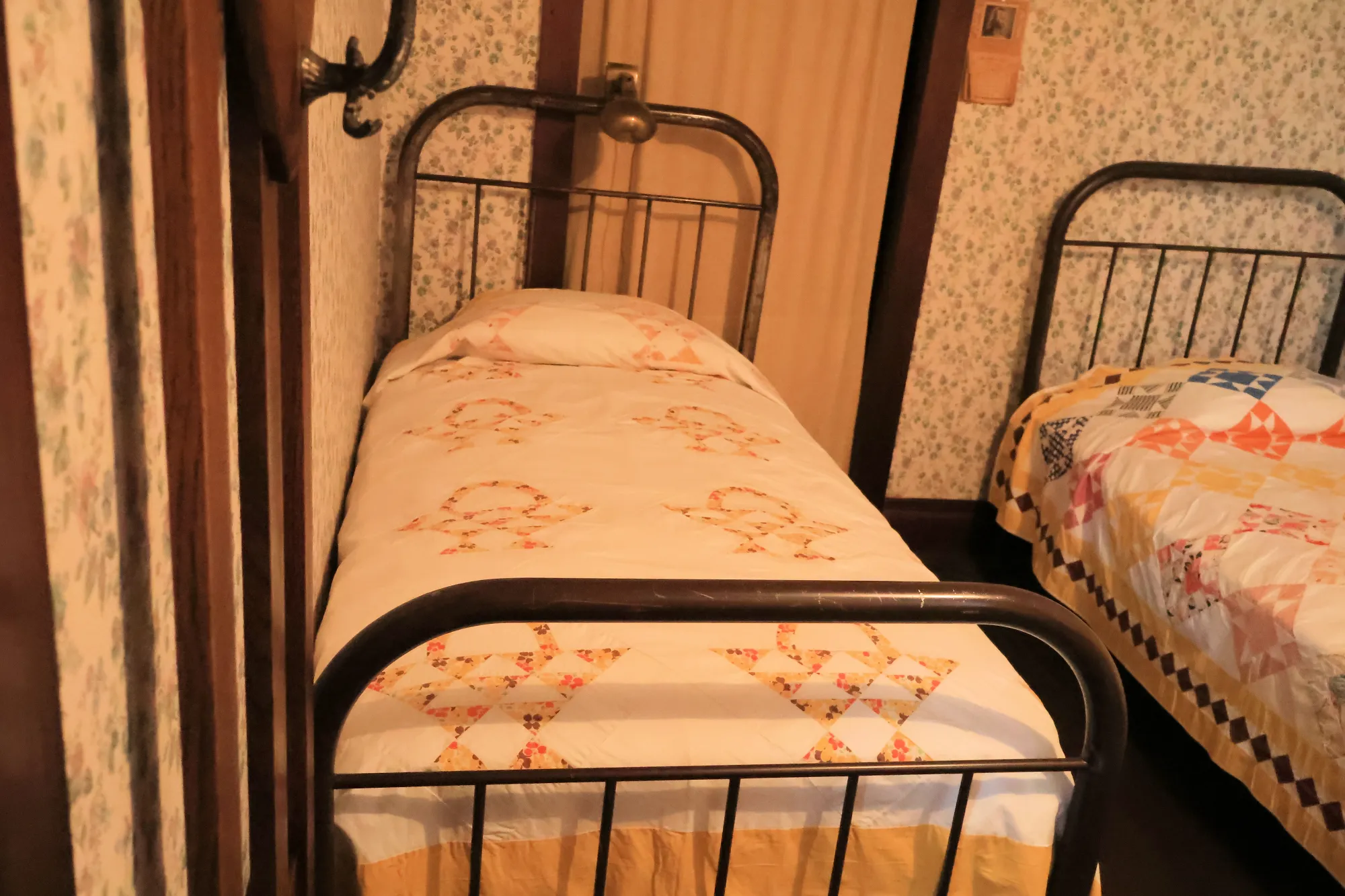 Historic bedroom with two iron twin beds and floral quilts in the Eisenhower Home