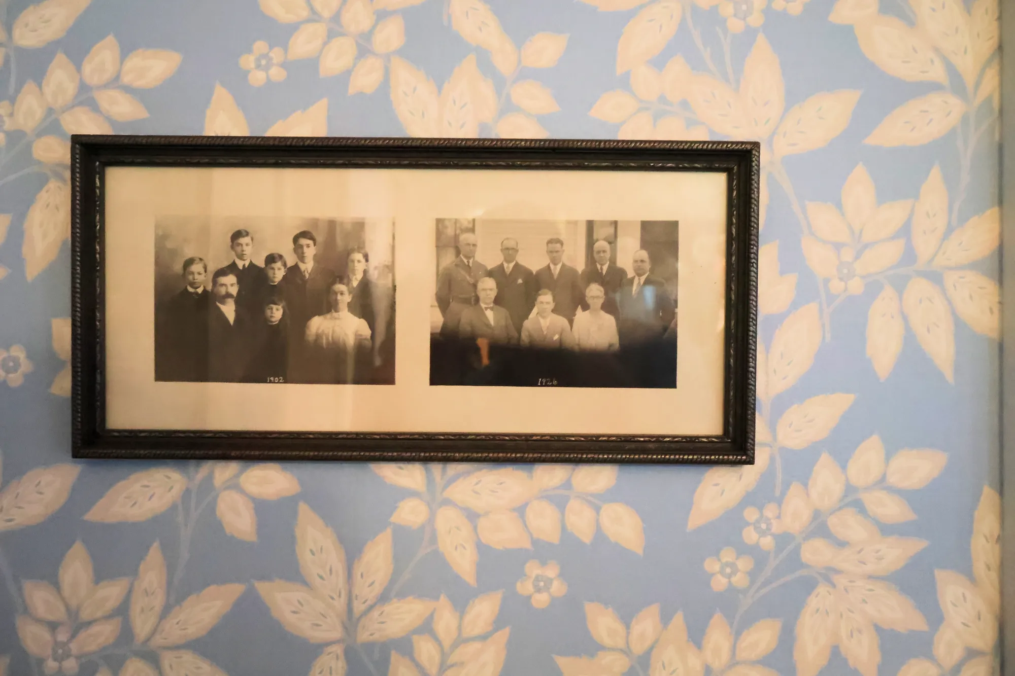 Framed black-and-white family photograph on blue floral wallpaper